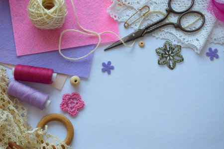 Bright flat lay with pink and violet threads scissors lace flowers and buttons on white background ideal for DIY handmade projects crafting and creative decorの写真素材