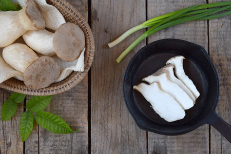 Top view of sliced king oyster mushrooms in a black rustic bowl with fresh herbs and green onions. Perfect for farm to table food photography, organic culinary visuals, and healthy vegetarian concepts.の写真素材