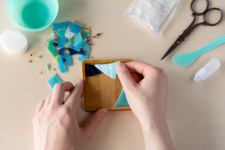 Faux stained glass fragments positioned in silicone mold to make handmade mosaic-style coaster with plaster powder and tools for home decor DIY project, step 1の写真素材