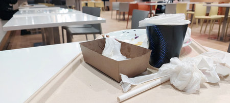 Tray with coffee cups napkins fast food box disposable plastic waste after meal mess public dining area clutter junk hygiene issue single use packaging trash accumulationの写真素材
