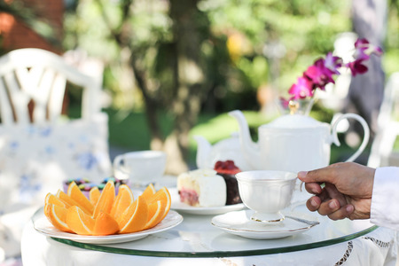 Afternoon tea and cakes and fruit orange in the gardenの写真素材