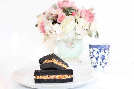 Sandwich with black bread with cup of coffee and flower