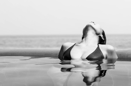 Asian woman relaxing in swimming pool on vacation in bikini in Thailandの写真素材