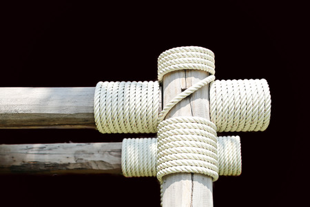 Layers of rope tied around a wooden log in black backgroundの写真素材