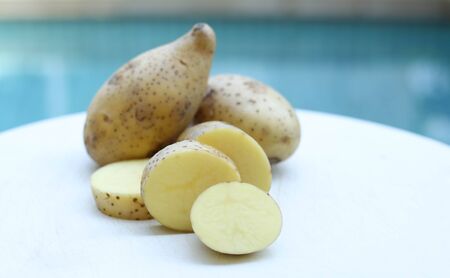 potatoes with segments on chopping broad in blue backgroundの写真素材