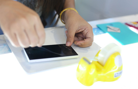 Woman applying a screen protector on an cellphone in the shop