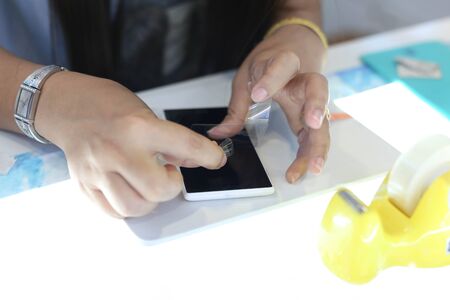 Woman applying a screen protector on an cellphone in the shopの写真素材