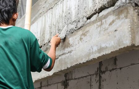 Asian boy hand using trowel with wet concrete wall in Thailandの写真素材