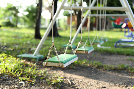 Old metal and wooden swing chair on the playground in the park in summer timeの写真素材