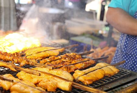 Man cooking chicken on barbecue in market placeの写真素材
