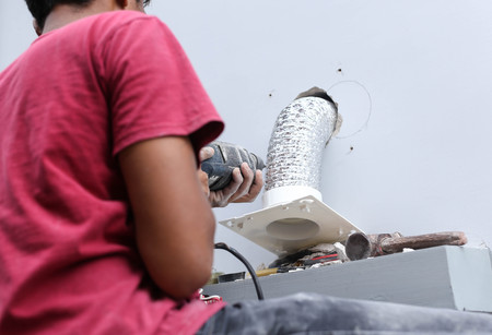 Unidentified builder making construction for ventilation on a building with screwdriver drillの写真素材