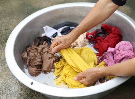 Hands wash stain of dirty clothes in big bowl