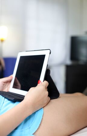 female relaxing in bed watching tabletの写真素材