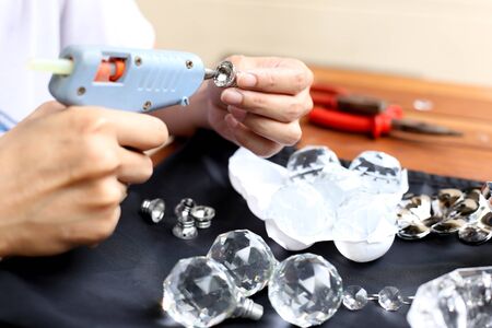 Woman fixing crystal lamps with hot glue gun for decorationの写真素材