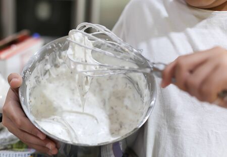 Young boy mixing flour with whisk for baking and cookingの写真素材