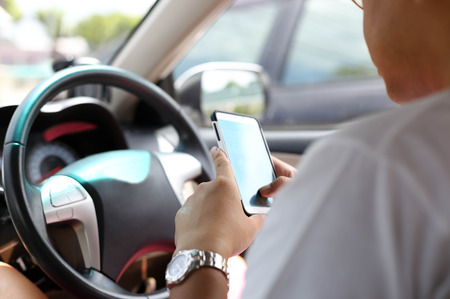 Unidentified man using smart phone while driving on the road