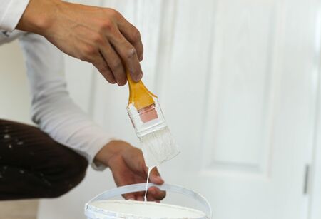 Painter hand holding yellow paint brush for decorating