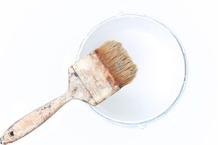 Old paint brush rest on top of  paint tin isolated in white backgroundの写真素材