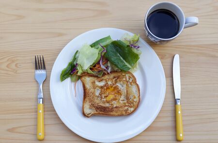 Breakfast fried egg on toast and green salad with cup of coffee