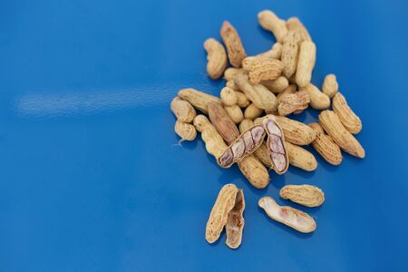 Half open penut on pile of penuts over blue background