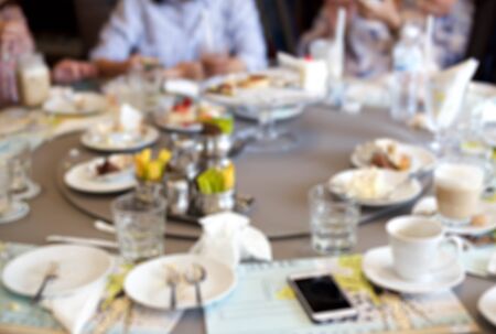Blurry group of people after having food and cake leftover on the tableの写真素材