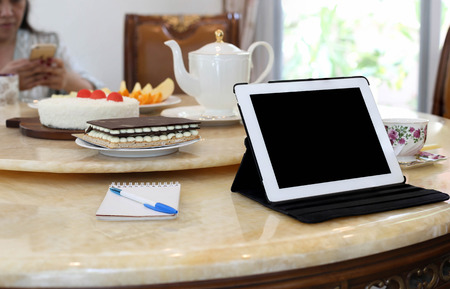 bussines people with tablet computer, pen, teapot and cake on the table