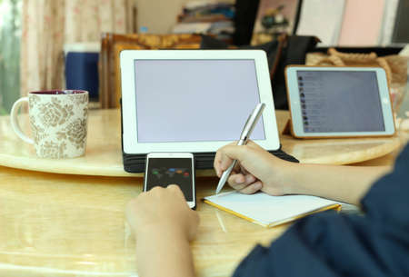 Business woman making notes and using a tablet and cell phoneの写真素材