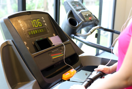 Woman exercise on the running machine at the gym and listen to cell phoneの写真素材