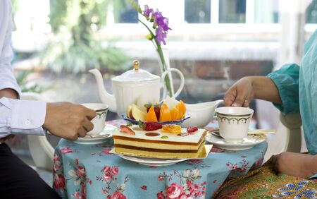 Asian business people having  tea and cake with fresh fruit on the tableの写真素材