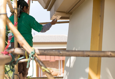 Painter on wooden scaffold painting  Exterior House with rollerの写真素材