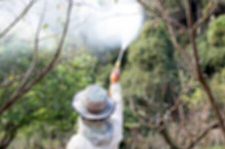 Blurred concept of gardener  spraying an insecticide a fertilizer to his plant