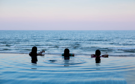 Silhouette of person head at swimming pool overlooking ocean at sunset