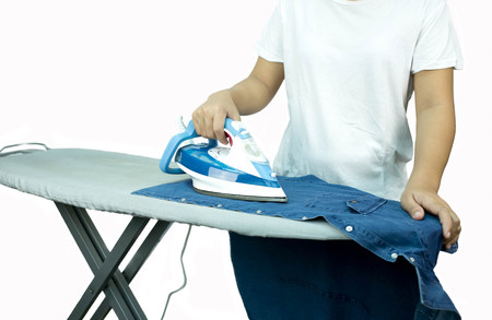Woman ironing a blue shirt with a steam iron in white backgroundの写真素材