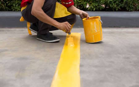 Man painting the yellow line on the concrete floor at car parkの写真素材
