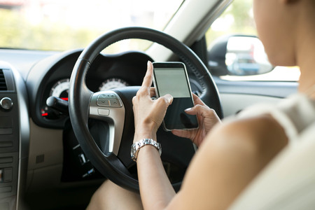 Woman sitting in car use mobile phone texting while driving dangerousの写真素材