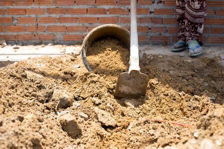 Construction workers are putting sand in the sand bucket in building siteの写真素材