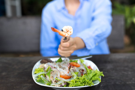 Hand holding fork with prawn and glass noodle salad with vegtableの写真素材