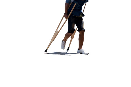 Man broken leg with stitching walking with crutches isolated in contrast and shadowの写真素材