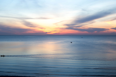 Beautiful sunrise sunset with fishing boats in the seaの写真素材