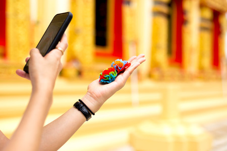 Woman taking photo of colorful fabric flower with mobile or cell phone