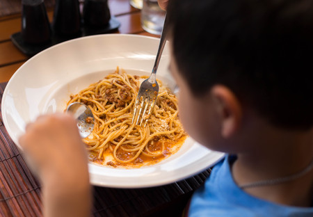 Selected focus little child enjoy eating spaghetti with bolognese at lunch timeの写真素材