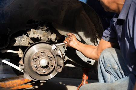 Selected focus on mechanic is hand holding wrench repairing brake system in a garageの写真素材