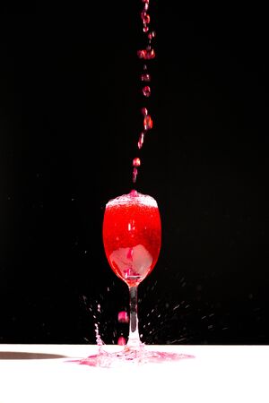 Speed testing pouring red water in a wine glass and splash ing in isolated on black backgrounの写真素材