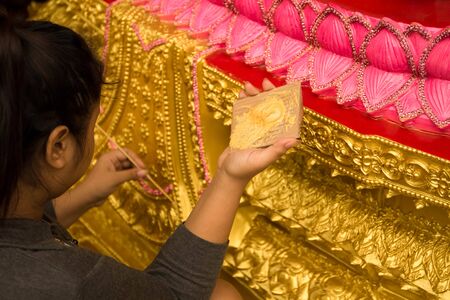 Woman painting buddha statue in gold color with small paint brushの写真素材