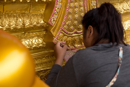 Woman handmade decorating the base of  Buddha statue in Thailandの写真素材