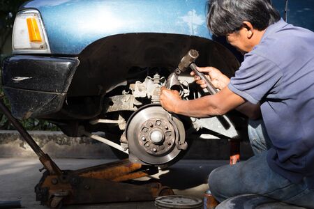 Mechanic repairing brake disk and detail of the wheel with hammerのeditorial素材
