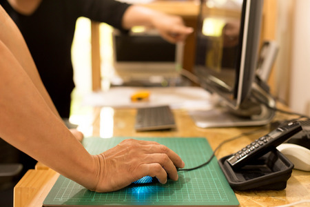 Concept Business man hand holding mouse with colleague looking at computer hand pointing at screenの写真素材