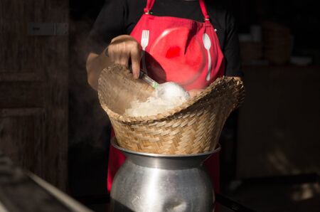 Woman cooking sticky rice or glutinous rice in bamboo wooden steamer old styleの写真素材