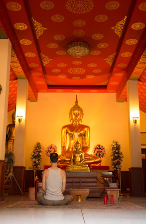 Man meditating in front of buddha statue in templeのeditorial素材