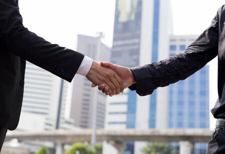 Business agreement hand shaking in front of modern building outdoorsの写真素材